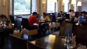 A restaurant with tables and chairs, large windows, and hanging lamps. - Jinjiang Inn Nanjing Train Station (Nanjing)