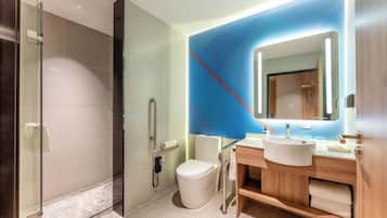 Un bagno moderno con box doccia in vetro, un water, un lavandino con specchio e mobili contenitori in legno.
