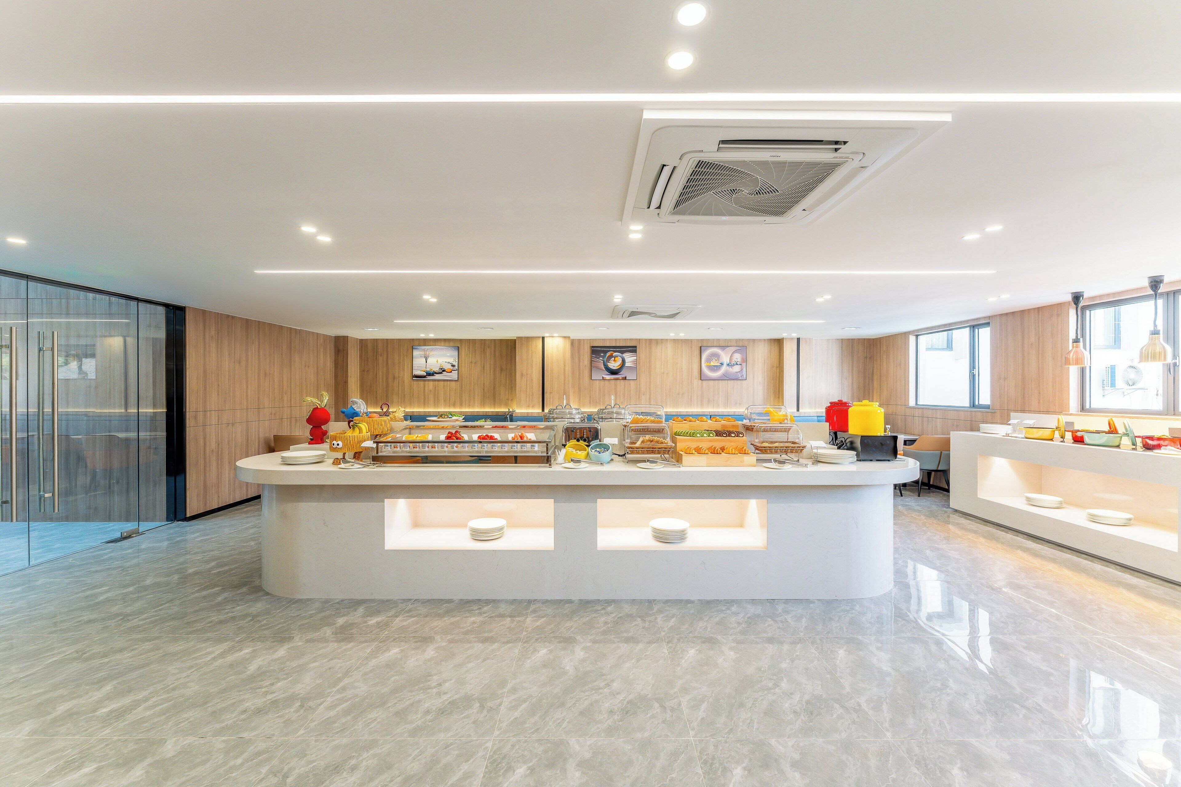 A modern kitchen with a central island, glass partitions, and a variety of food items displayed.