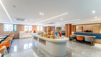 A modern dining area with a central buffet, long communal tables, and a variety of seating options.