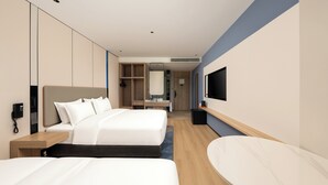 Une chambre d’hôtel avec deux lits, une télévision, un bureau et un miroir.