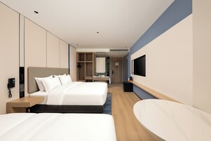 A hotel room with two beds, a TV, a desk, and a mirror.
