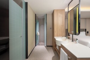 Un moderno baño de hotel con dos lavamanos, un espejo grande y una zona de ducha.