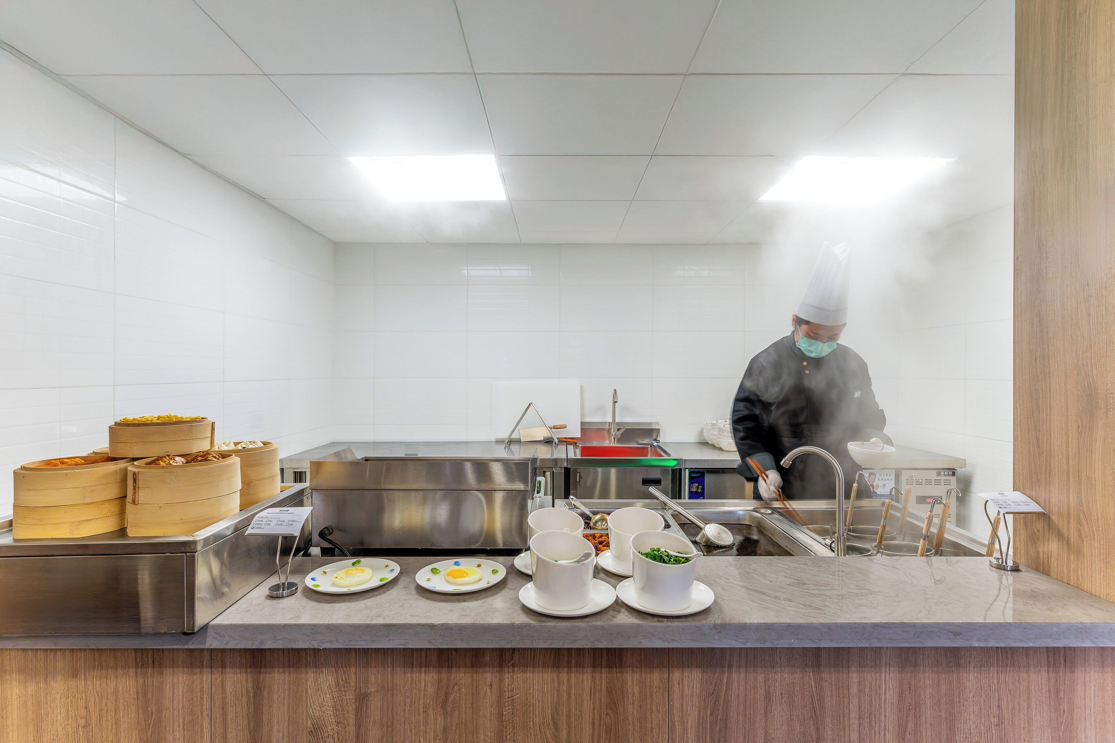 Una cocina con electrodomésticos de acero inoxidable, un mostrador de alimentos y una persona cocinando.