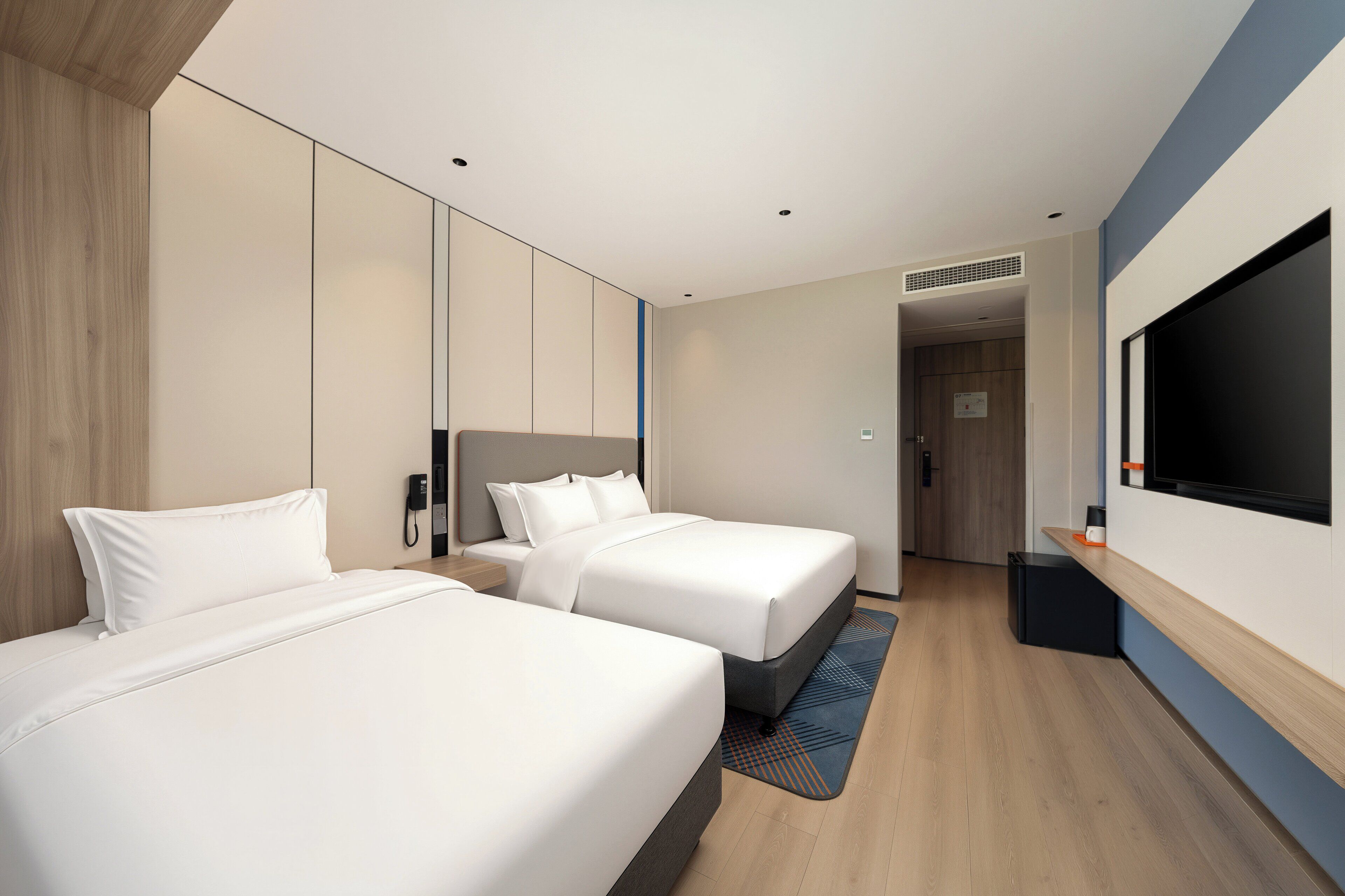 Habitación de hotel con dos camas, televisión, teléfono y un pequeño escritorio.