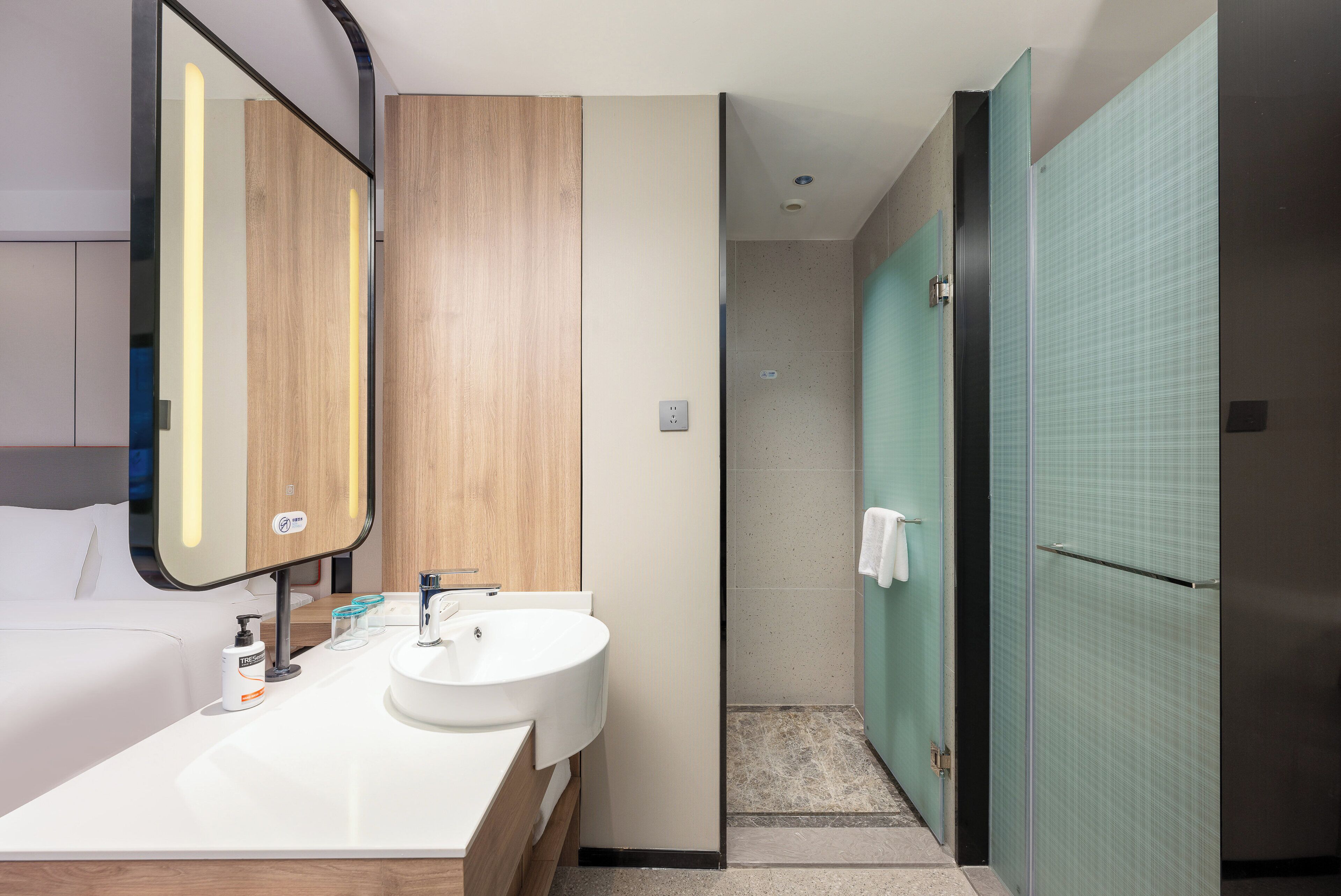 A modern bathroom with a double sink, a mirror, and a shower area.