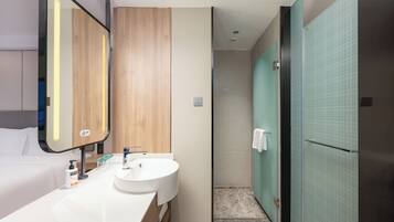 A modern bathroom with a double sink, a mirror, and a shower area.