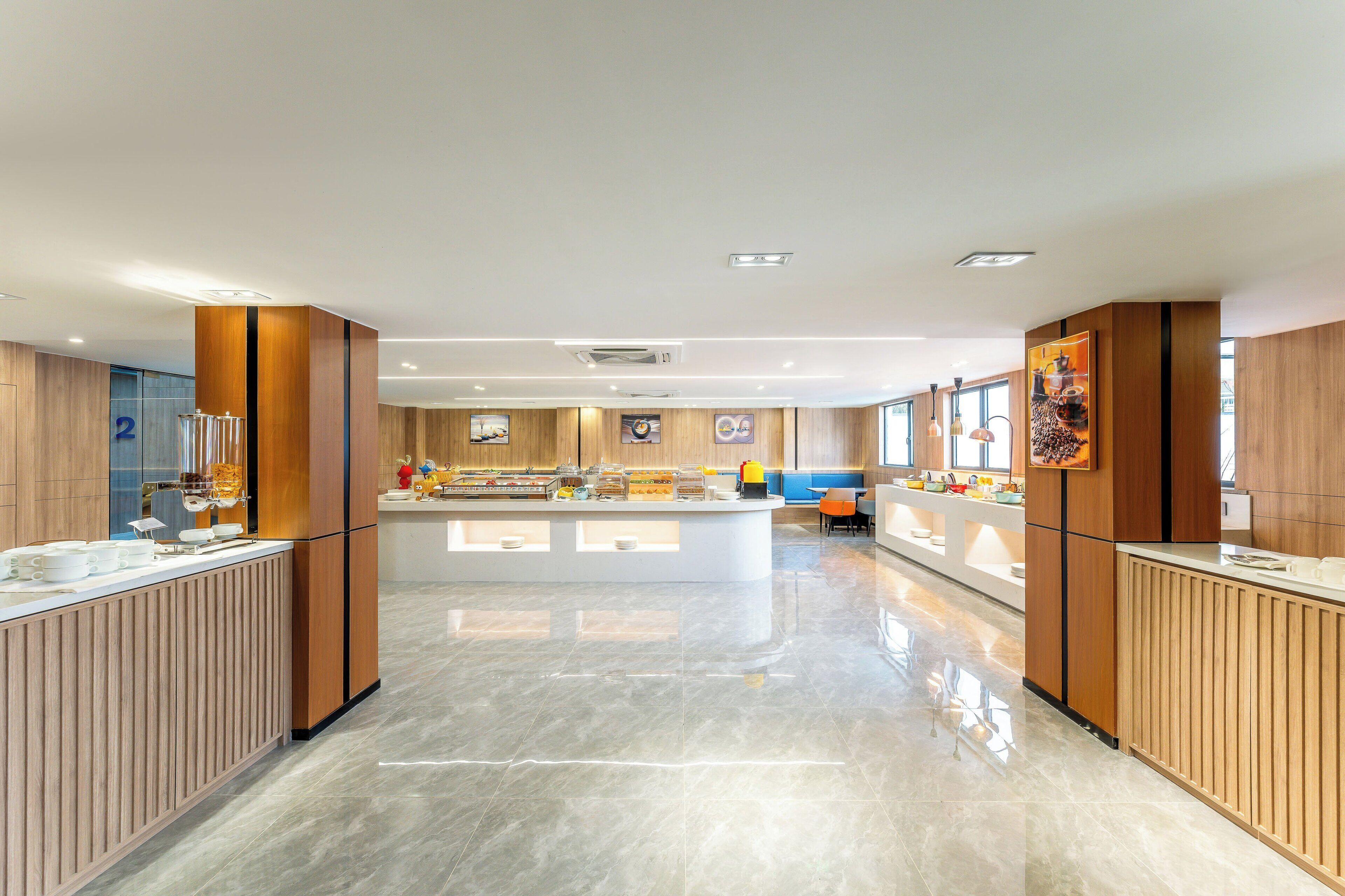 Un moderno vestíbulo de hotel con una recepción central, zona de buffet y arreglos de asientos.
