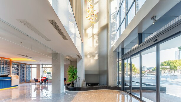 A modern hotel lobby with a reception desk, seating area, and large windows offering views of the city. - Holiday Inn Express Suzhou Shantang Street (Suzhou)