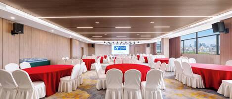 A conference room with multiple tables and chairs, large windows, and a city view.
