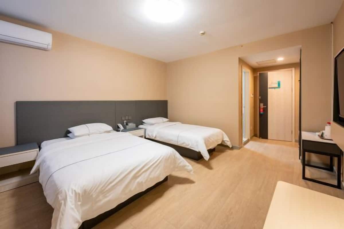 A hotel room with two beds, a desk, and a chair.