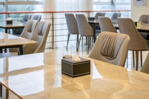 A clean, modern dining area with marble tables and upholstered chairs. - Jinjiang Inn (Suzhou baodai ditiezhan dian) (Suzhou)