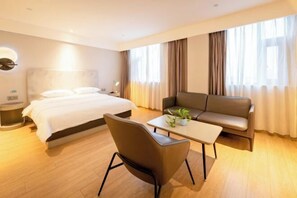 A hotel room with a bed, a sofa, a coffee table, and a chair. - Jinjiang Inn (Suzhou baodai ditiezhan dian) (Suzhou)