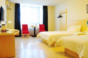 Une chambre d’hôtel avec deux lits, un bureau, une chaise et une petite table.