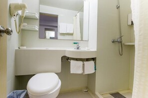 Une salle de bain comprenant des toilettes, un lavabo, un miroir et une douche.