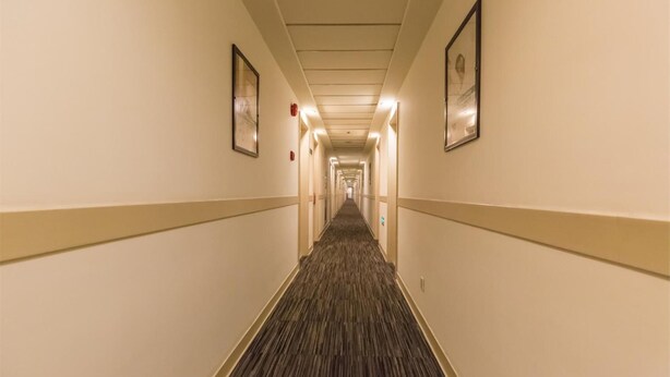A hotel hallway with carpeted floors, beige walls, and framed artwork on the walls. - Jinjiang Hotel (Suzhou Mudu Zhujiang Road) (Suzhou)