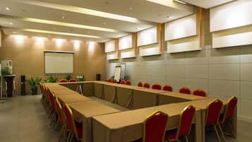 A conference room with a long table, red chairs, a projector screen, and a whiteboard.