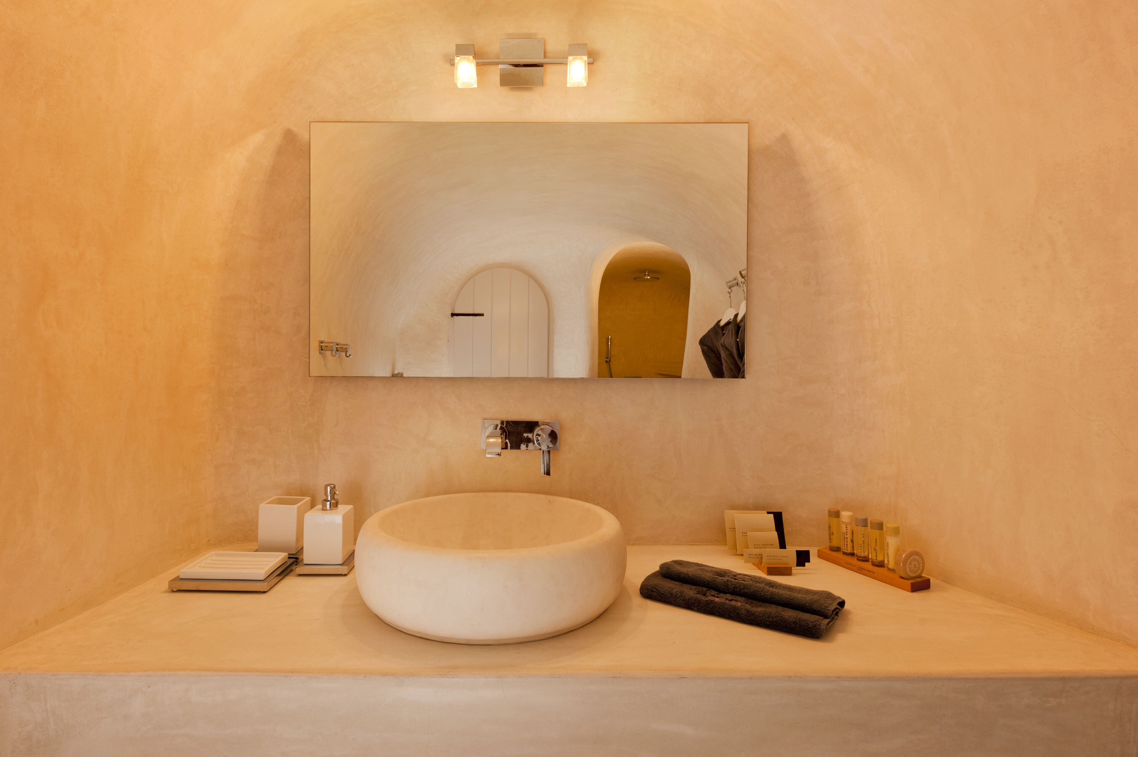 Un baño moderno con un lavabo redondo, un espejo y un perchero para toallas.