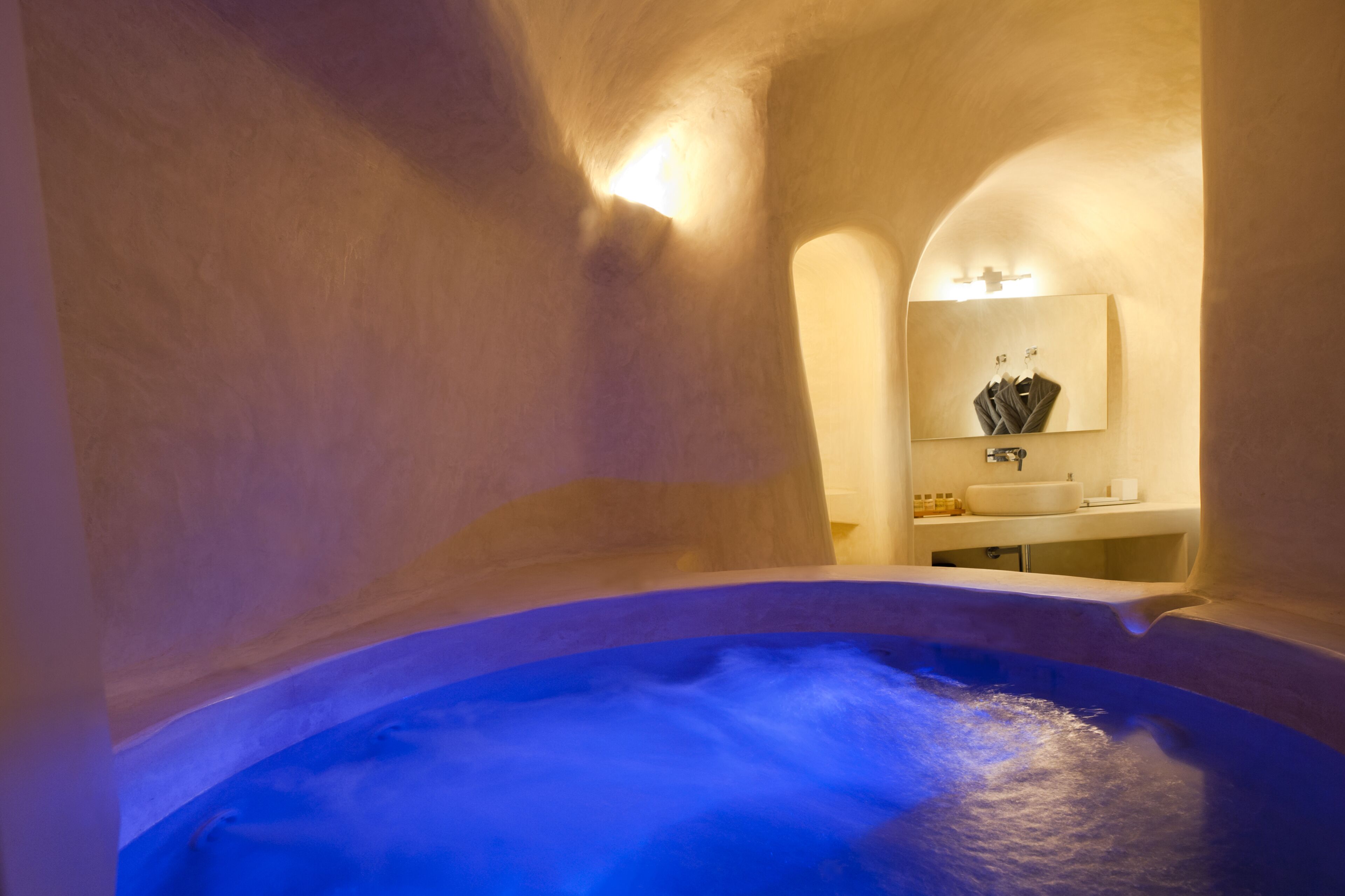 Un espacio de spa con una bañera de hidromasaje, un lavabo y un espejo.