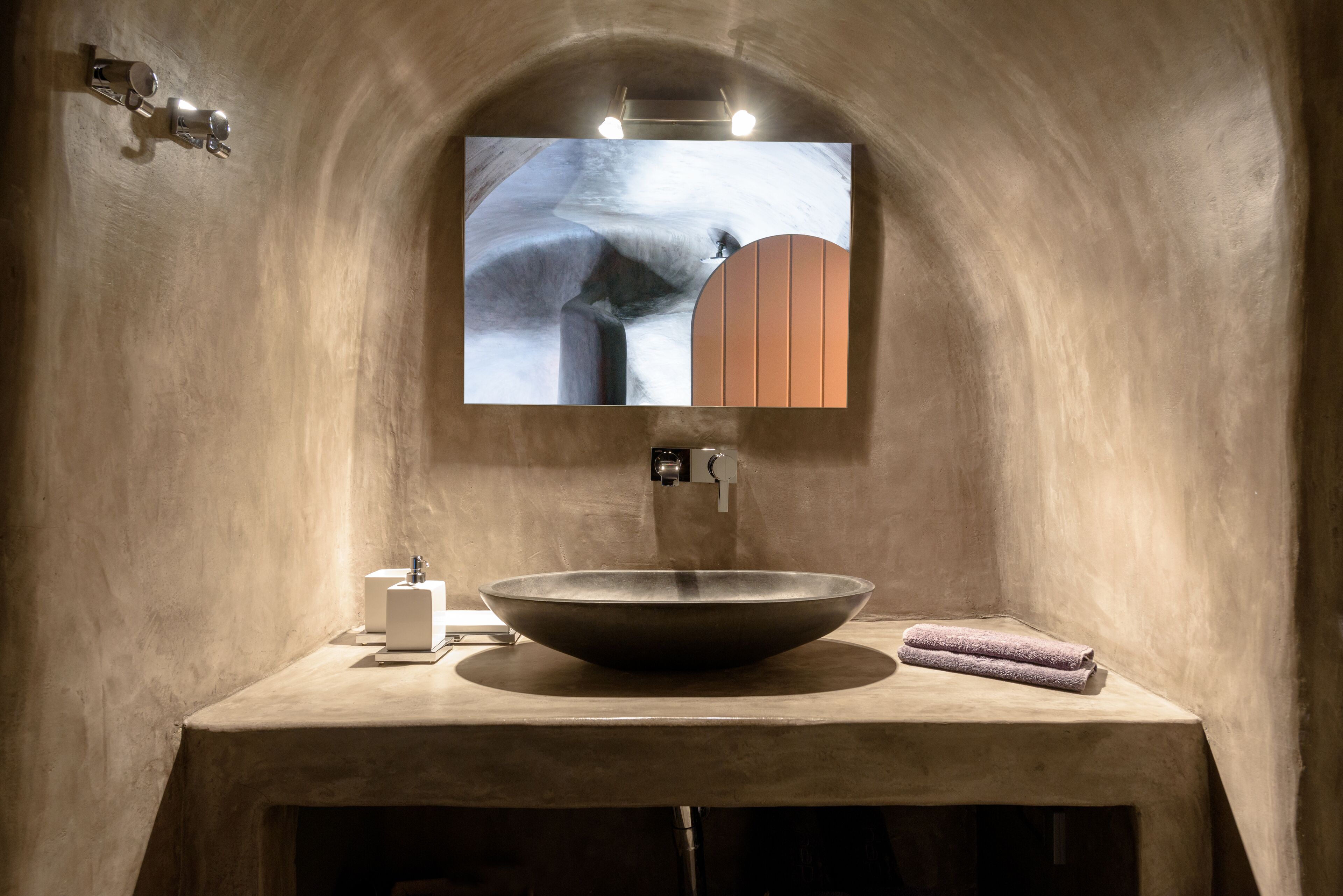 Un baño moderno con un lavamanos grande, un espejo y una toalla sobre el mostrador.