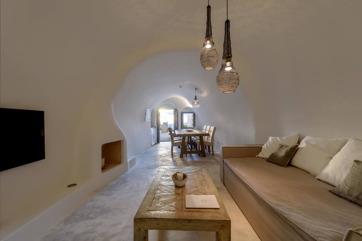 A spacious living area with a wooden coffee table, a beige sofa, and a dining area in the background.