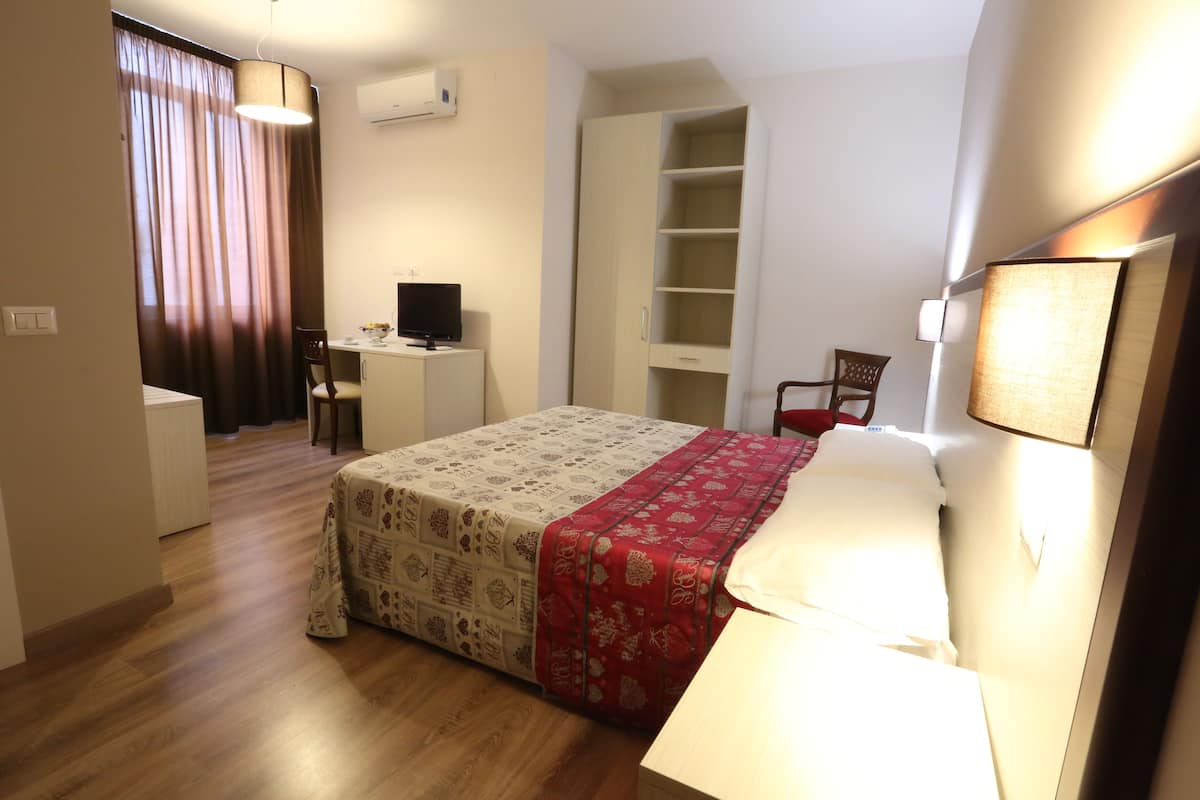 Ein Hotelzimmer mit Bett, Schreibtisch, Stuhl und Fernseher.