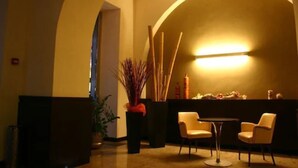 A warmly lit indoor space with a curved wall, a small round table, and two chairs. - Hotel Europa (Foggia)