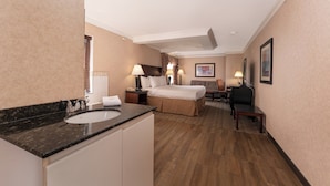 A hotel room with a marble bathroom vanity, a bed with a headboard, a desk, and a chair.
