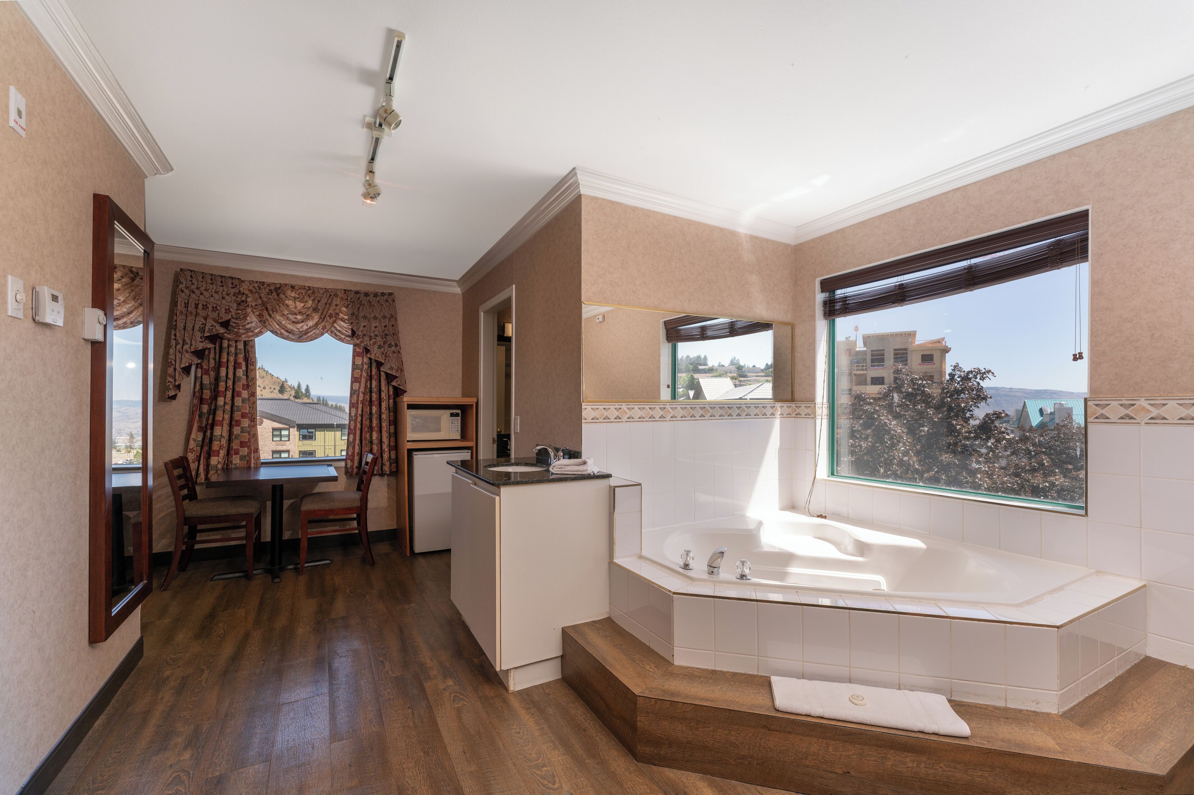 Un baño moderno con bañera, lavamanos y ventana con vistas a la ciudad.
