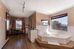 A modern bathroom with a bathtub, a sink, and a window offering a city view.
