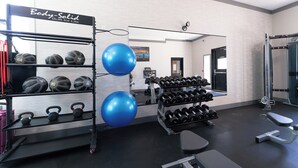 A gym with exercise equipment, including kettlebells, dumbbells, and exercise balls.