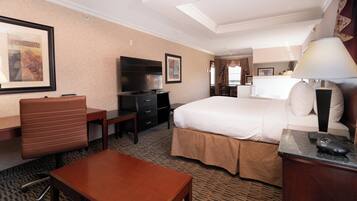 A hotel room with a bed, desk, chair, TV, and a small table.
