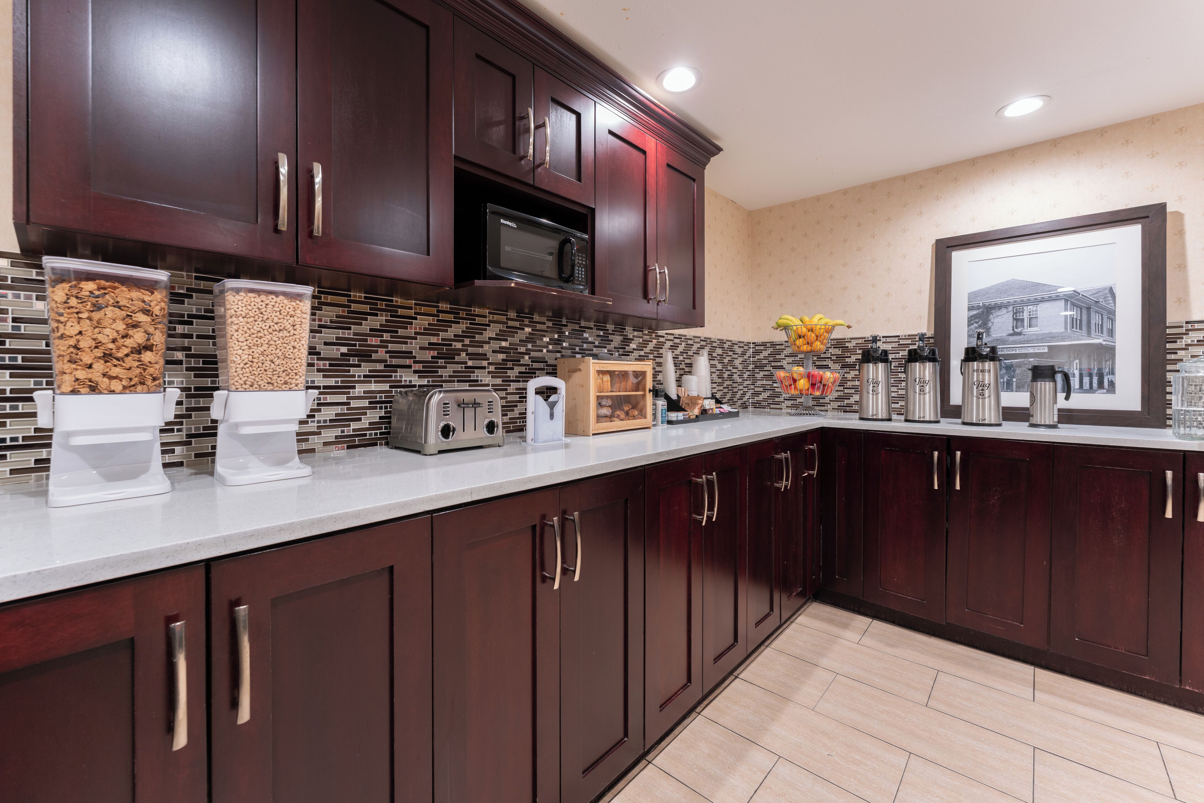 A modern kitchen with dark wood cabinets, a microwave, and a tiled backsplash.