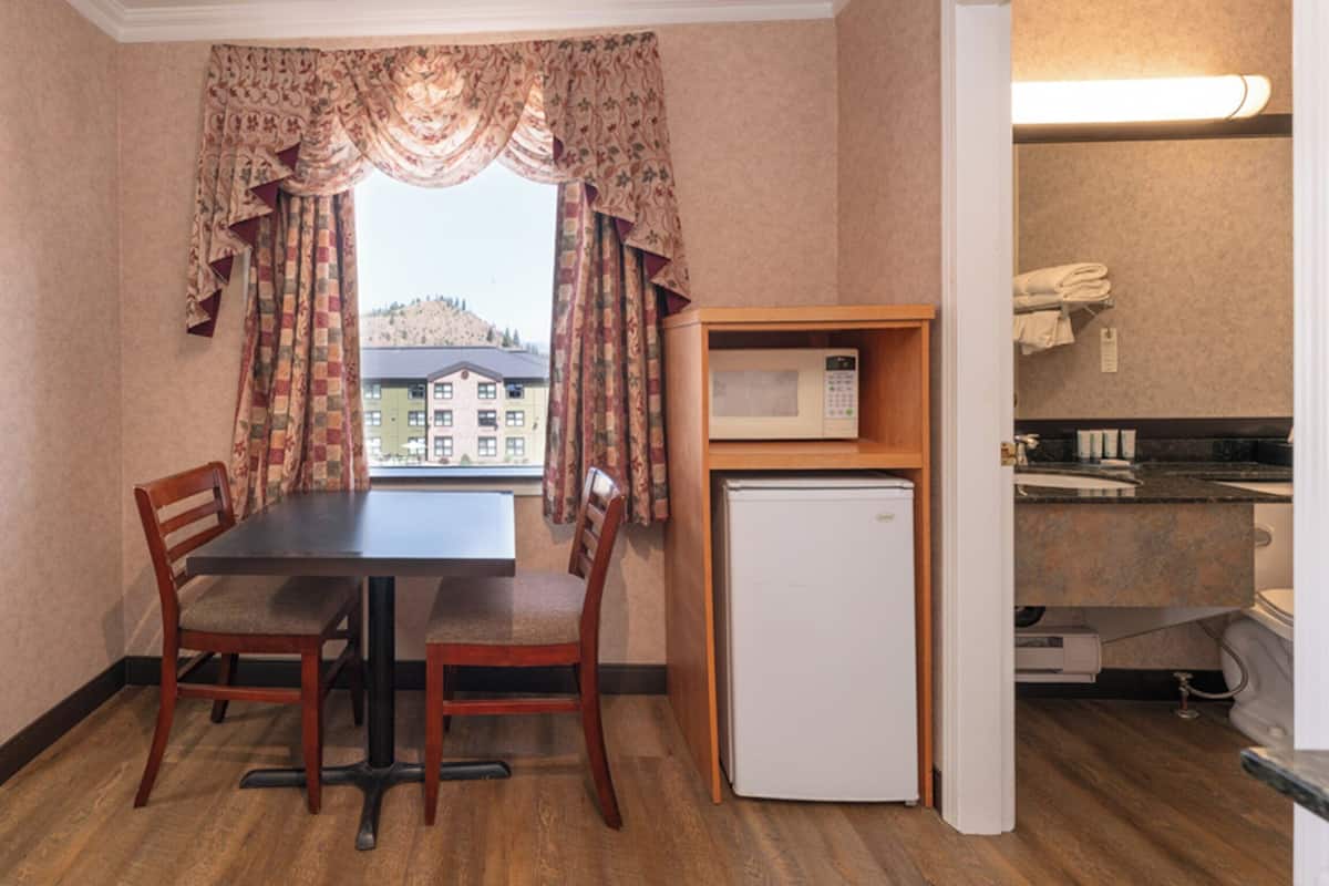 A compact kitchen with a dining table, chairs, a microwave, and a refrigerator.