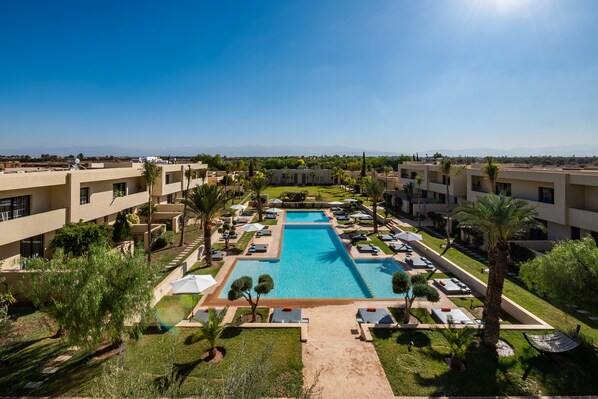 A resort with a central swimming pool, multiple lounge areas, and a clear view of distant mountains.