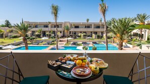 A balcony with a breakfast spread, overlooking a pool and a resort building. - Sirayane Boutique Hotel and Spa (Marrakech)