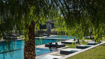 Relax by the serene pool surrounded by lush greenery and a well-maintained lawn.