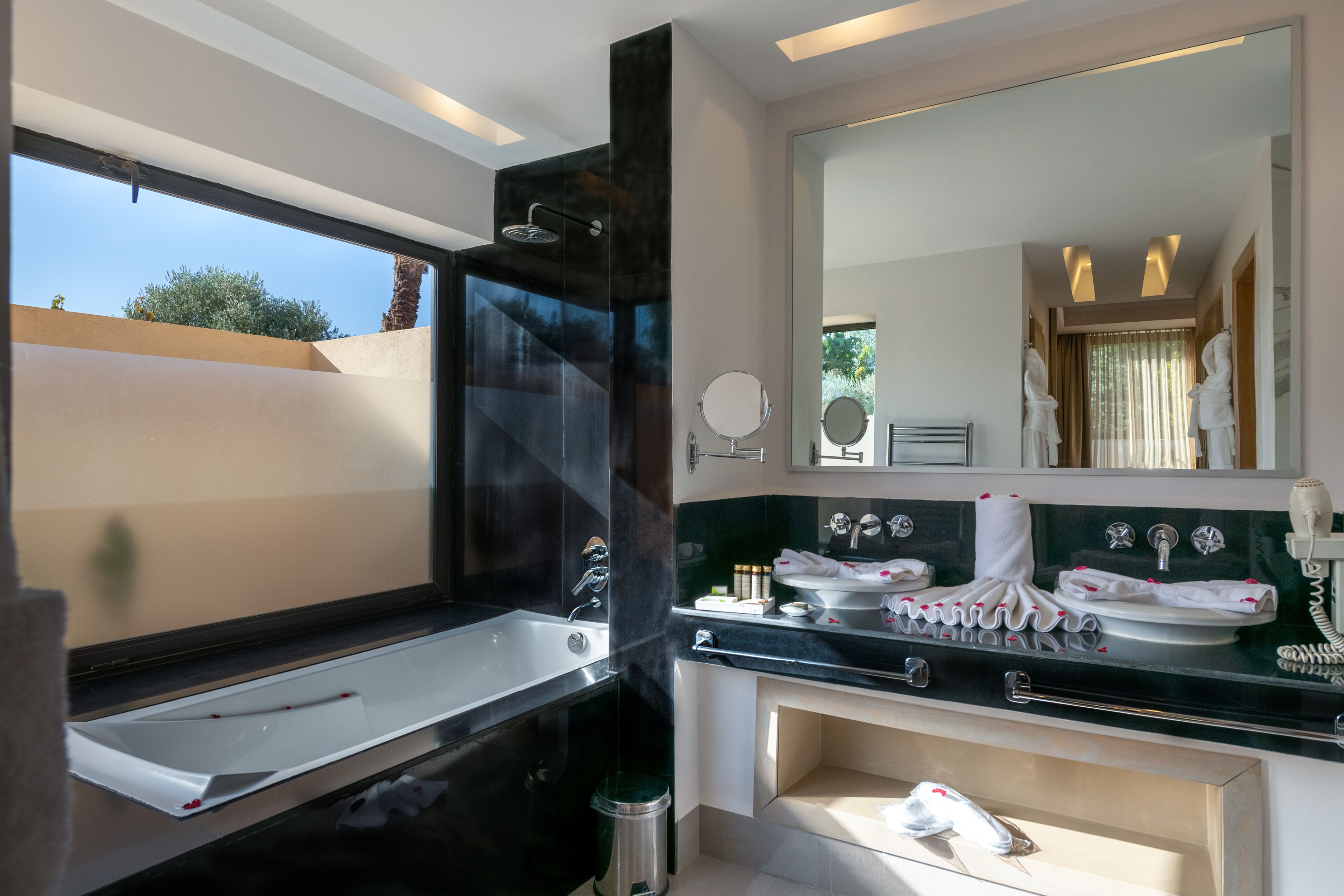 Un baño moderno con una bañera grande, una zona de ducha separada y un tocador con espejo y lavabo.
