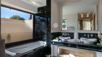 Un baño moderno con una bañera grande, una zona de ducha separada y un tocador con espejo y lavabo.