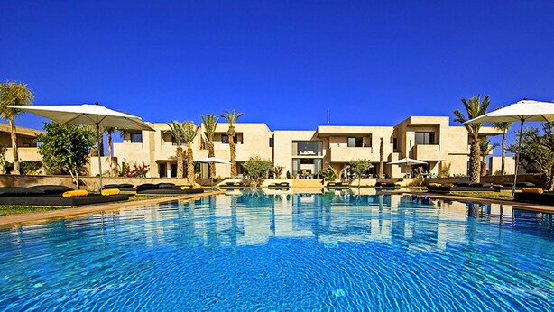 A swimming pool with lounge chairs and umbrellas, surrounded by buildings with a modern architectural style. - Sirayane Boutique Hotel and Spa (Marrakech)