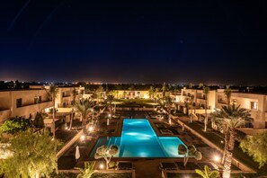 A nighttime view of a resort with a central swimming pool, surrounded by palm trees and well-lit pathways. - Sirayane Boutique Hotel and Spa (Marrakech)