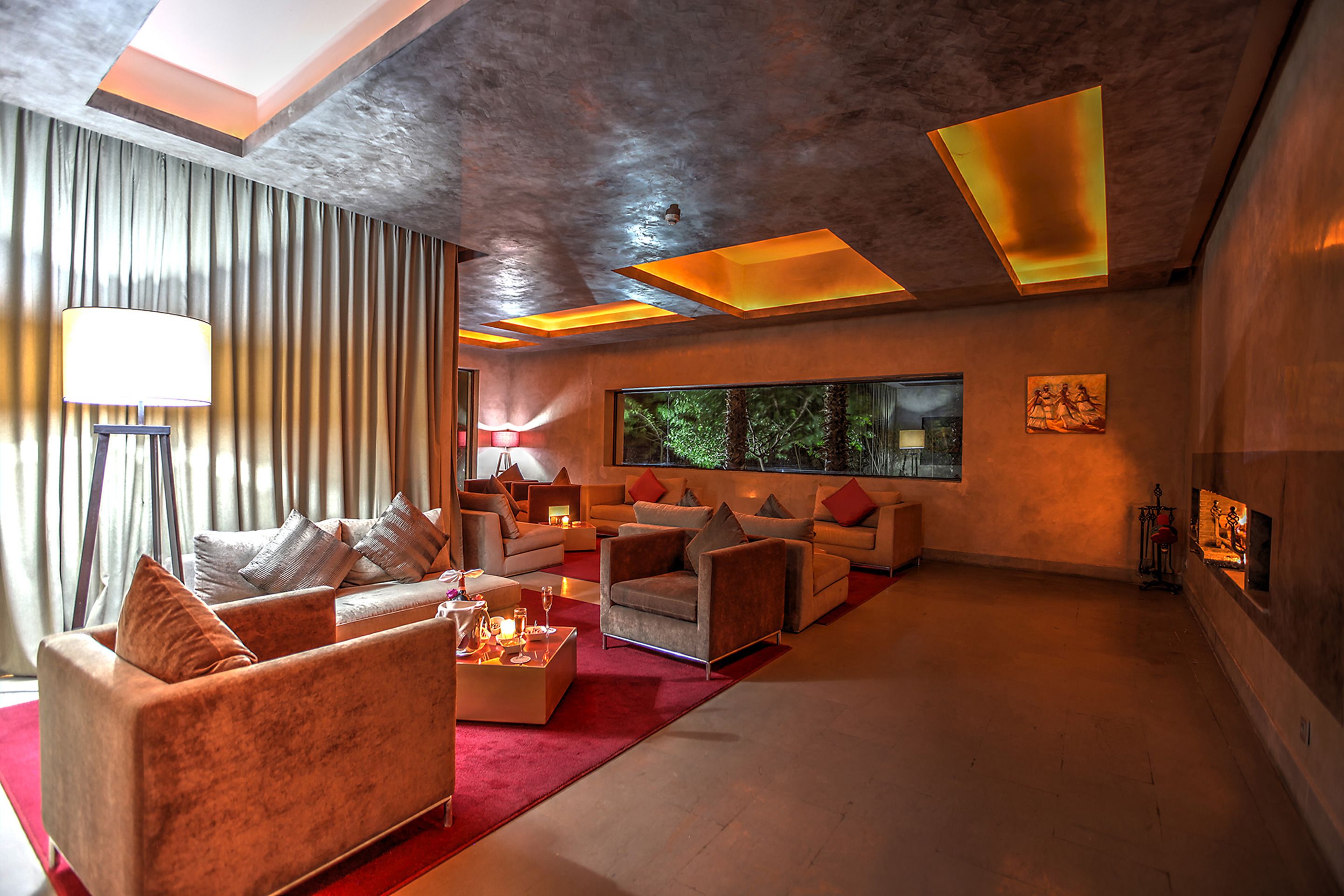 A spacious living area with multiple sofas and a large window providing a view of trees.