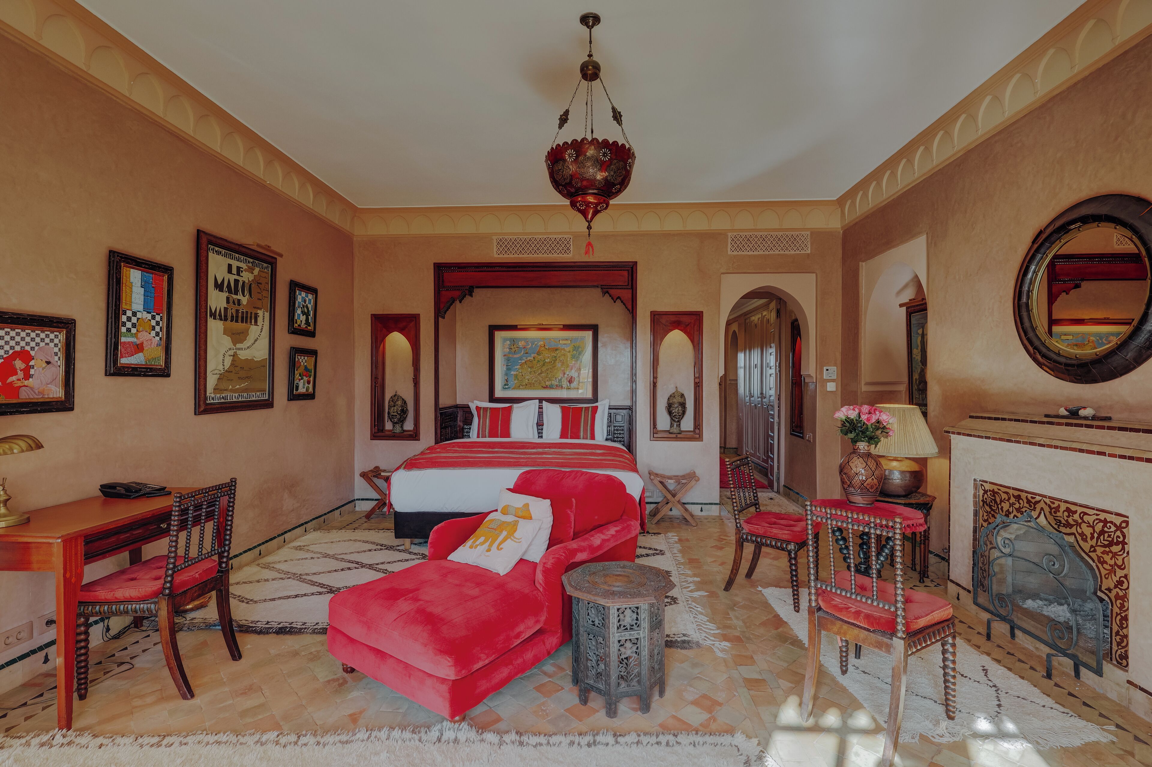 Un dormitorio espacioso con una cama grande, un sofá rojo, un escritorio de madera y una chimenea.
