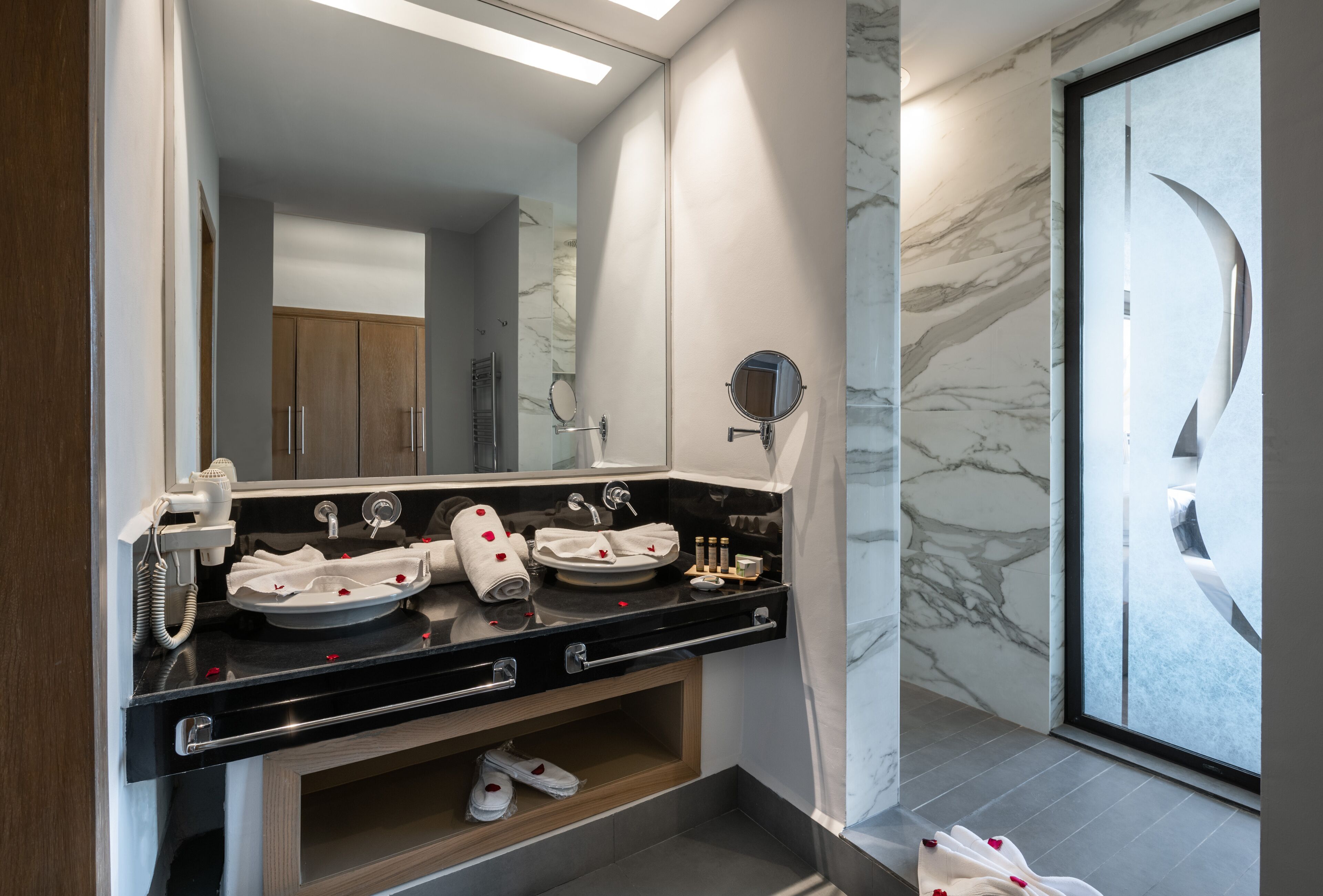 Un baño moderno con encimera negra, dos lavamanos, un espejo y un mueble de tocador.