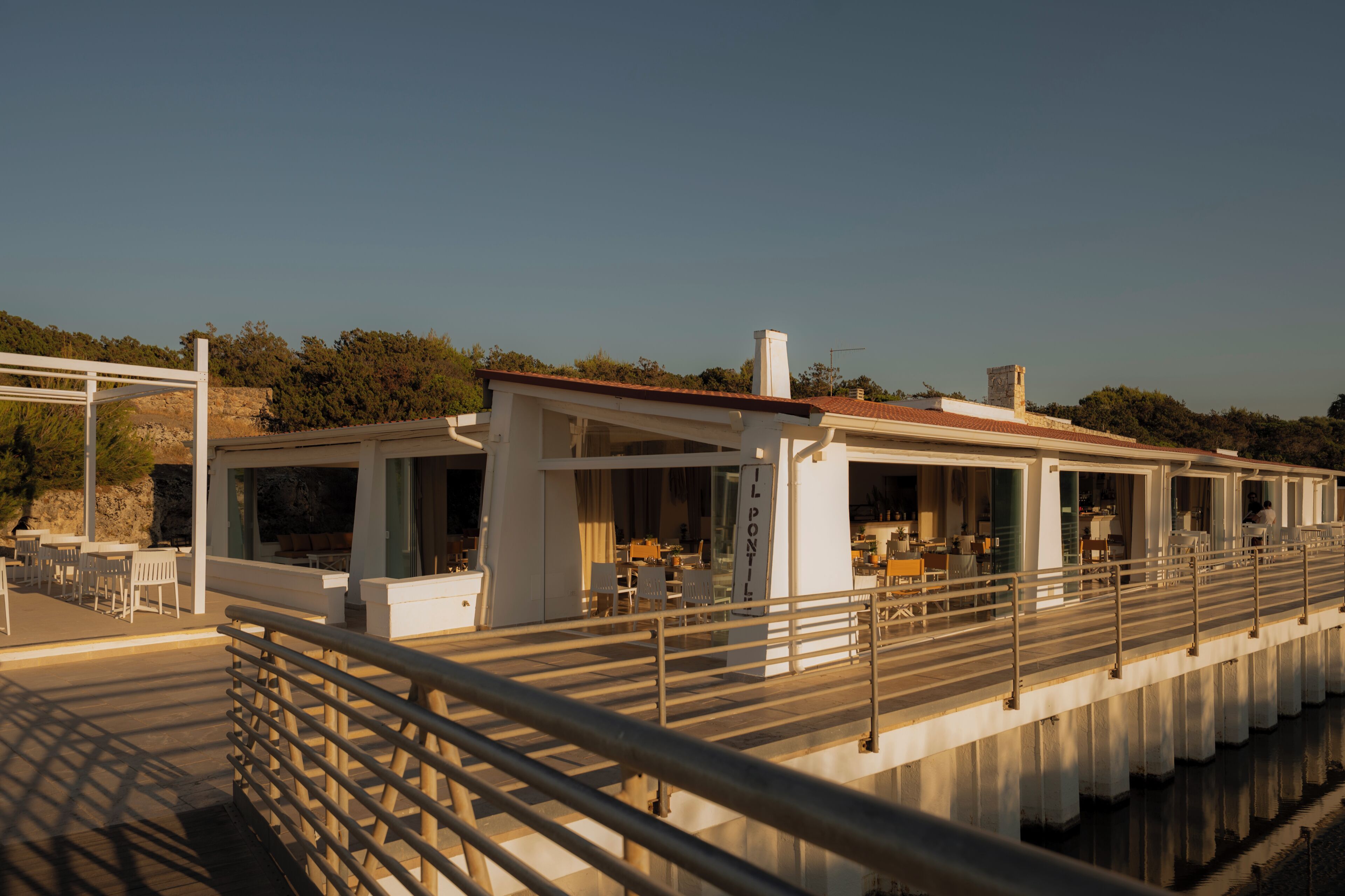A waterfront restaurant with outdoor seating, a covered area, and a view of the water.