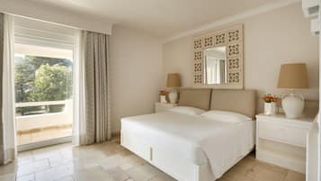 Une chambre à coucher avec un grand lit, une table de chevet, une commode, un miroir et une fenêtre avec des rideaux.