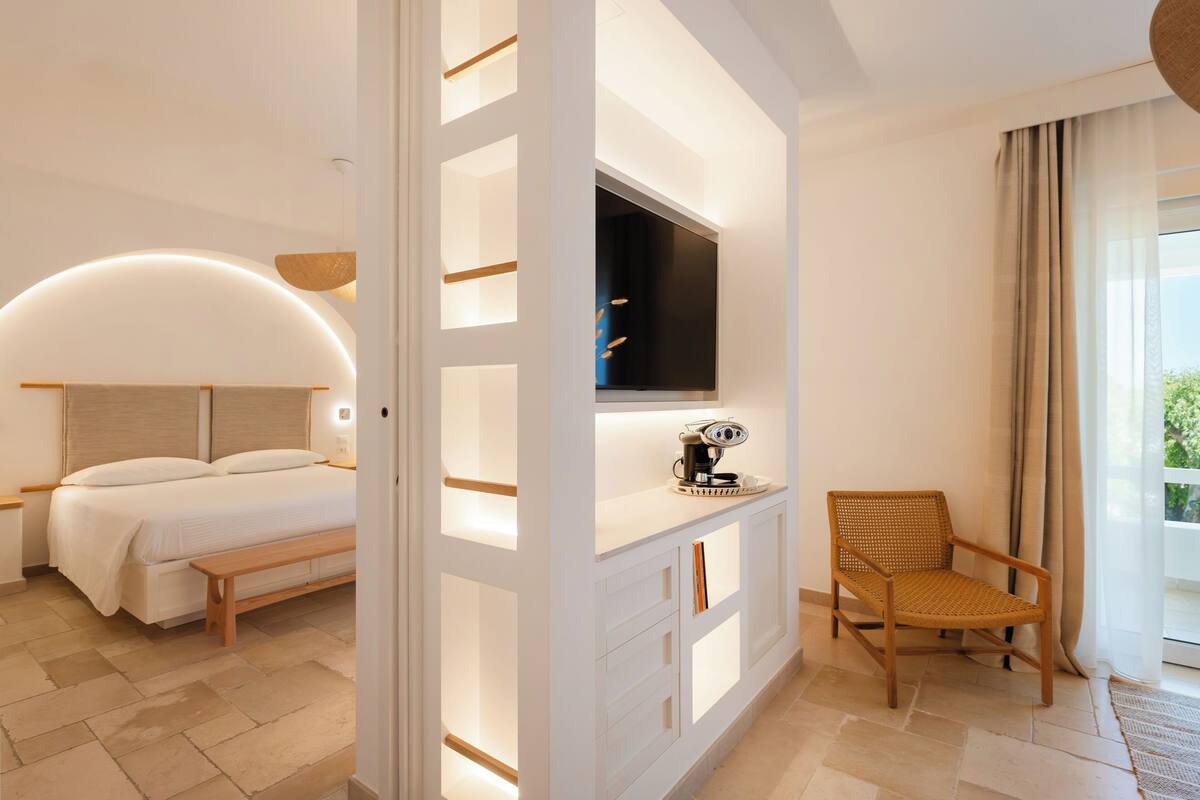 A modern hotel room with a bed, a TV, a desk, and a chair.