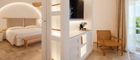 A modern hotel room with a bed, a TV, a desk, and a chair.
