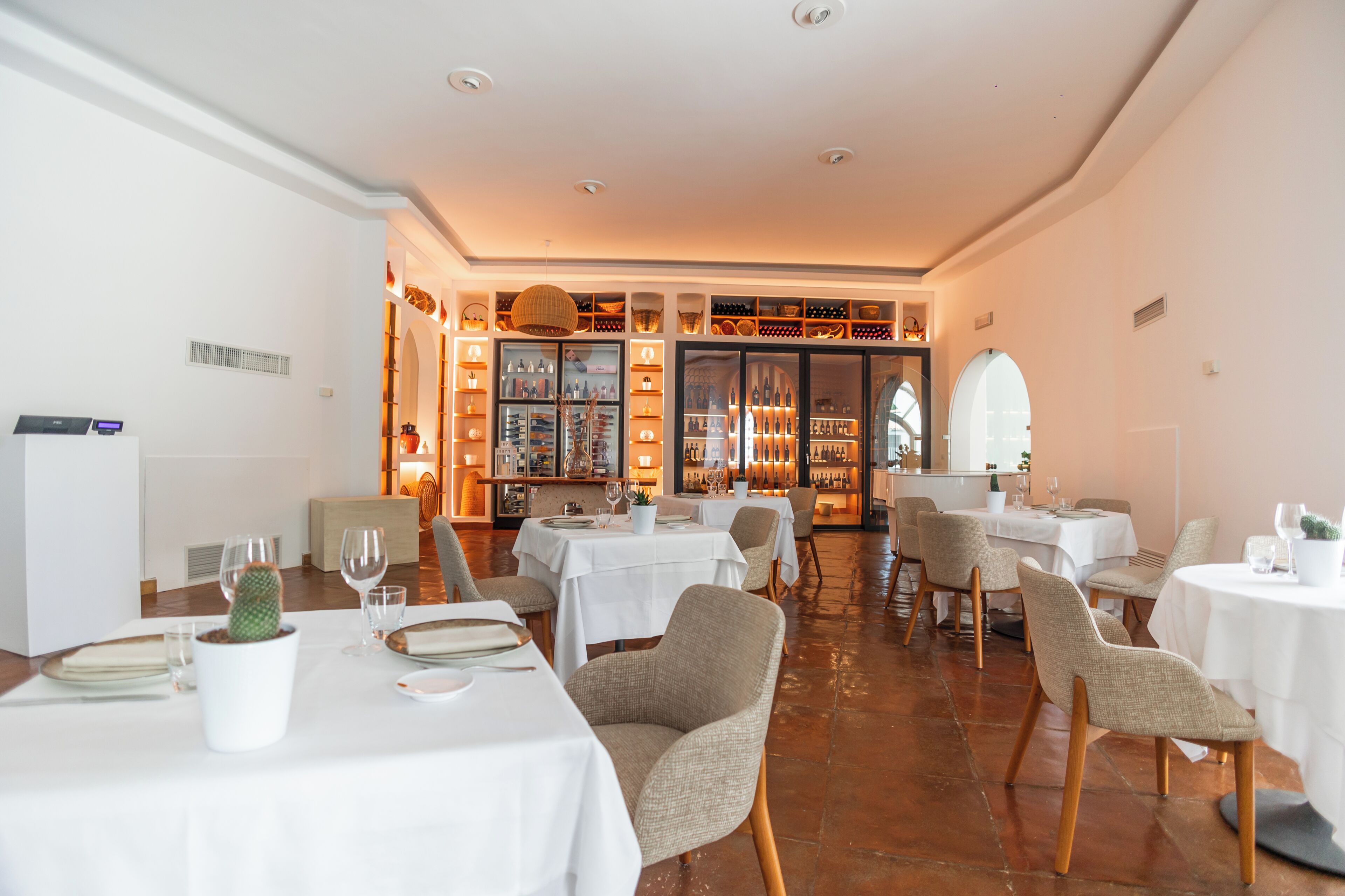 Un restaurant doté de nombreuses tables, de chaises et présentant une variété de bouteilles de vin.