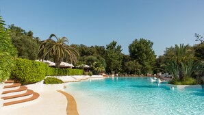 A resort pool with clear blue water, surrounded by lush greenery and palm trees. - Ostuni a Mare (Ostuni)